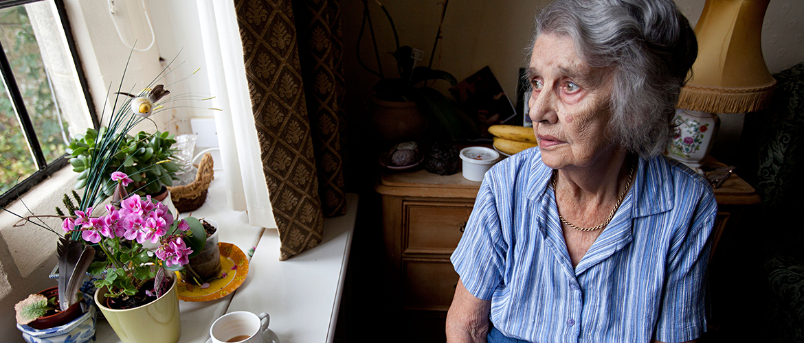 Vrouw met dementie kijkt uit het raam van verzorgingstehuis